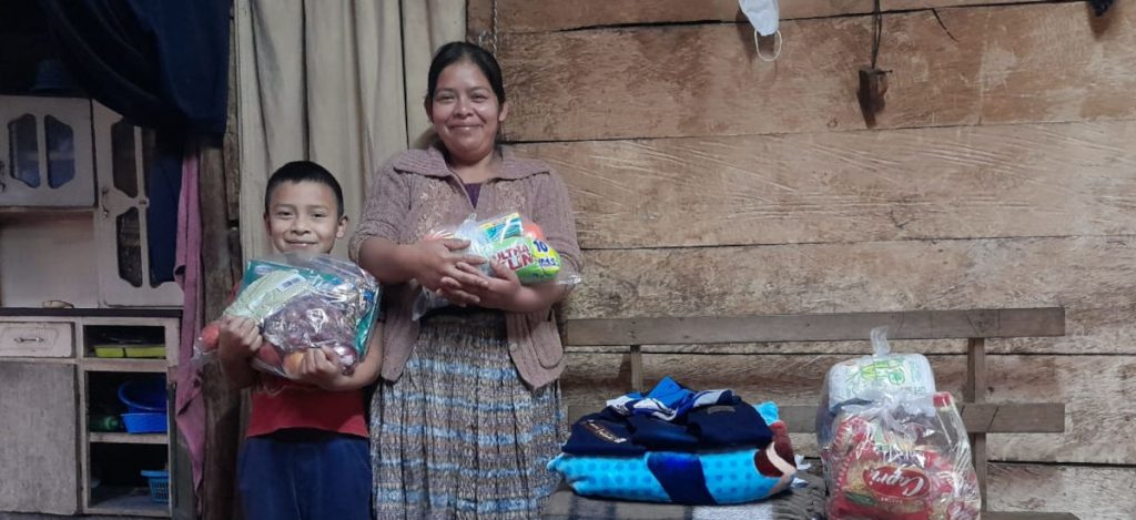 Jhon and his mother smiling with a food package