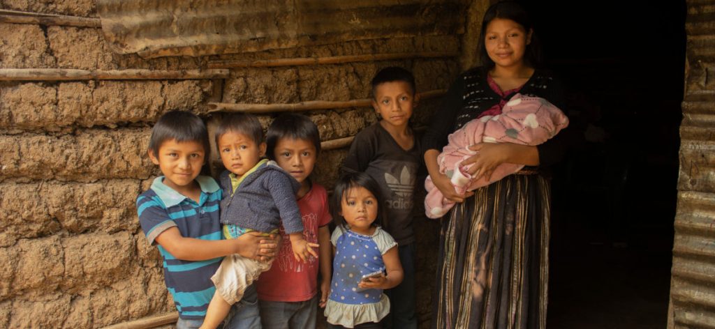 Mother and six children in front of a mud and stick house